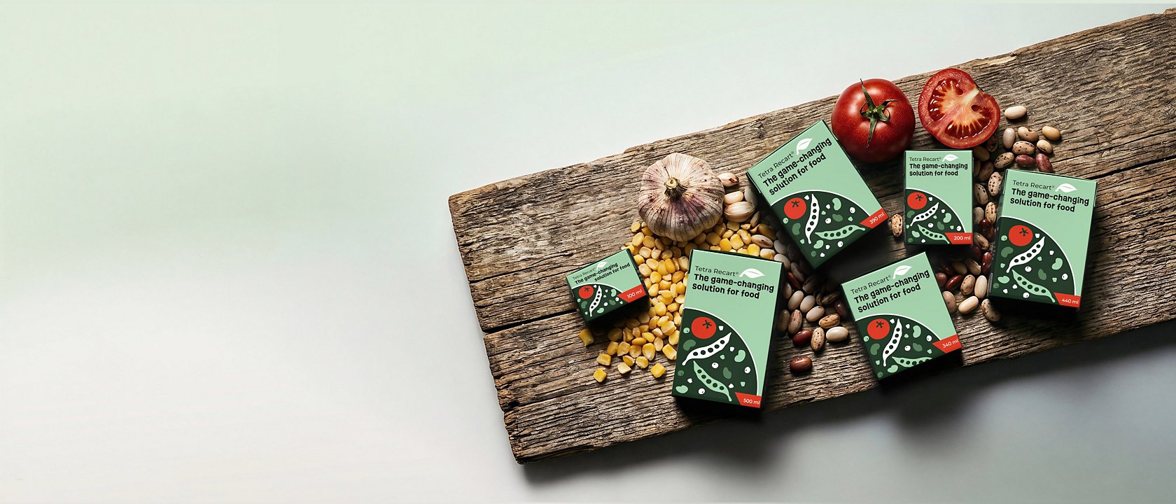 Tetra Recart carton packages, corn, beans and fresh tomatoes on wooden cutting board